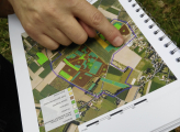 A person points at an area on a map with their index finger